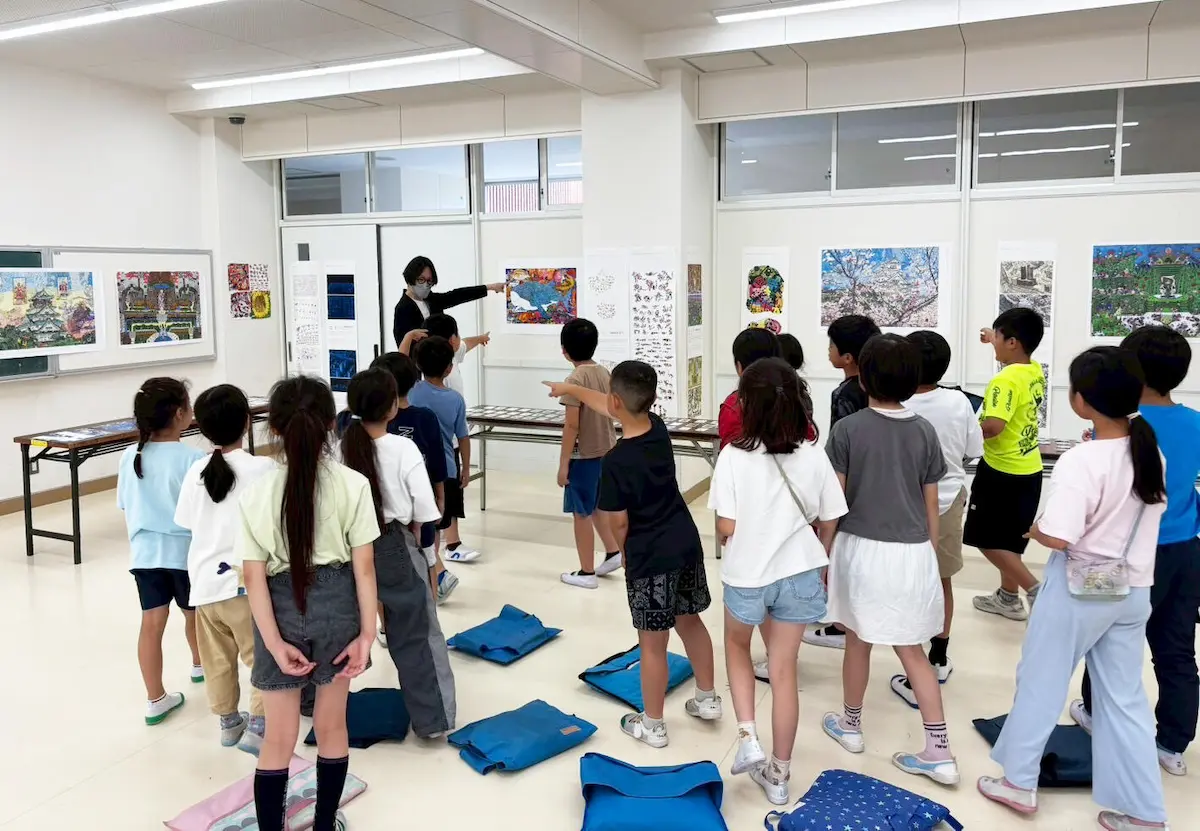 展示されている作品の前で学生たちと対話をしながら作品を紹介している様子の写真