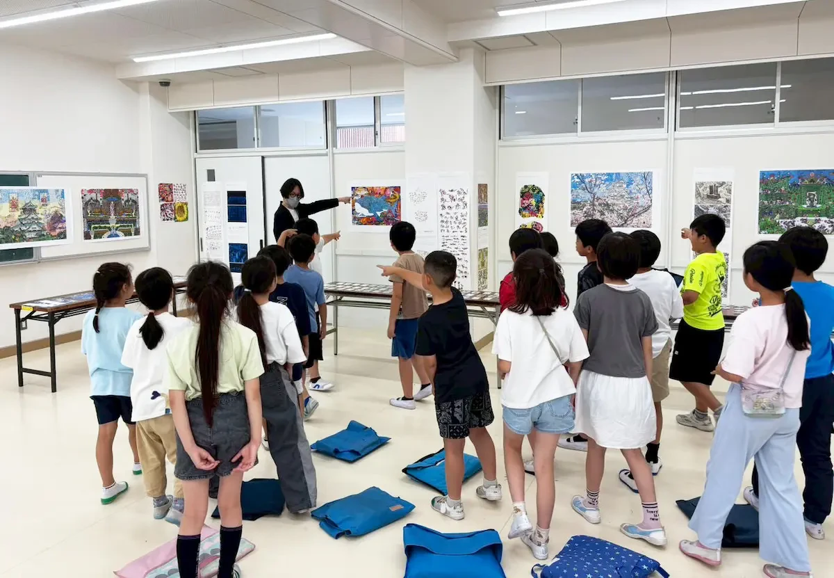 展示されている作品の前で学生たちと対話をしながら作品を紹介している様子の写真