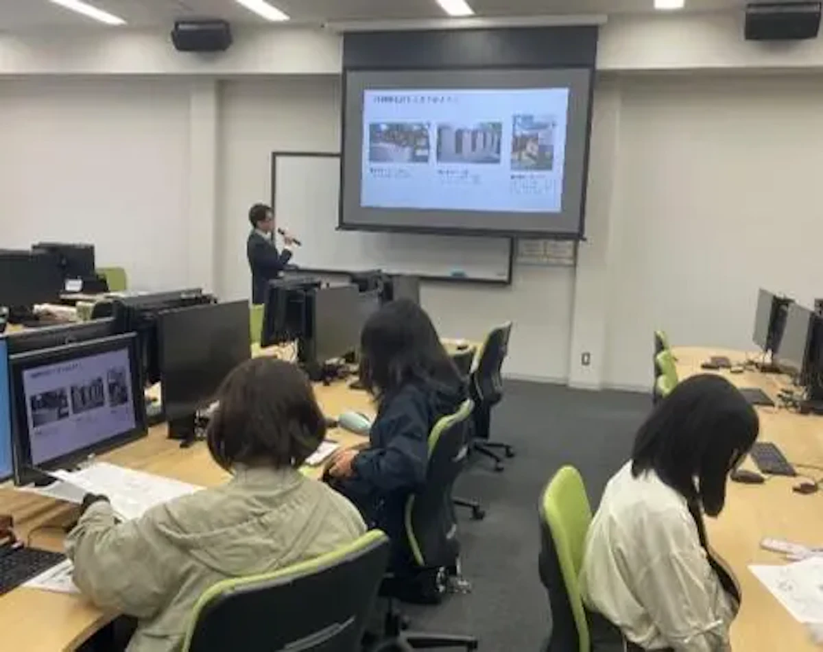 スクリーンにスライドを映しながら印刷機械の仕組みなどを説明している様子の写真