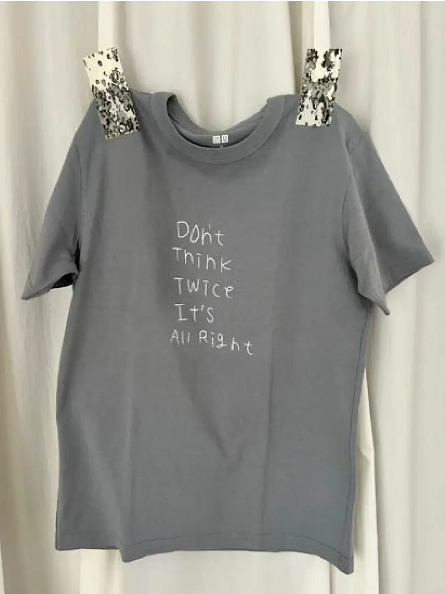 グレーのTシャツを広げた状態で展示されている様子の写真