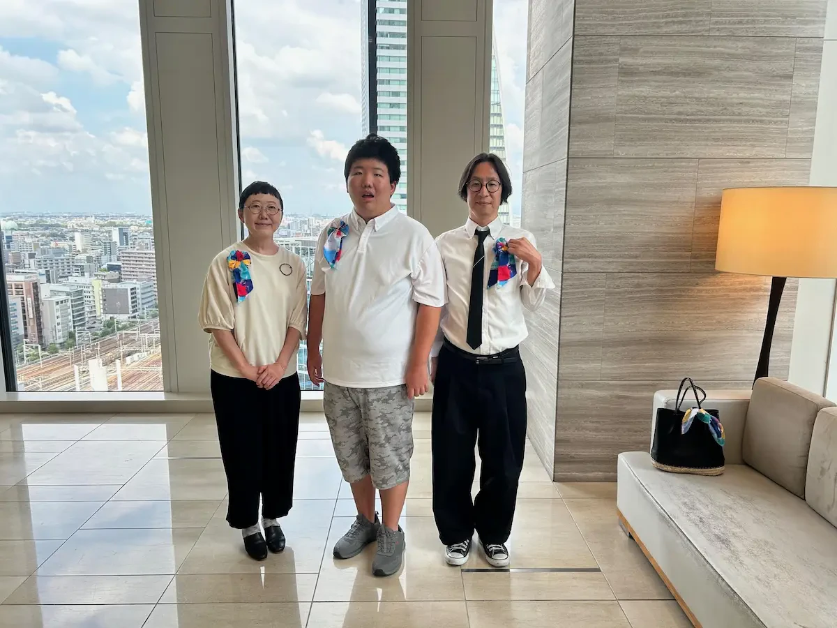 高層階からの名古屋の景色を背に伊山英吾さんと伊山英吾さんのお母さまと当社男性社員の集合写真