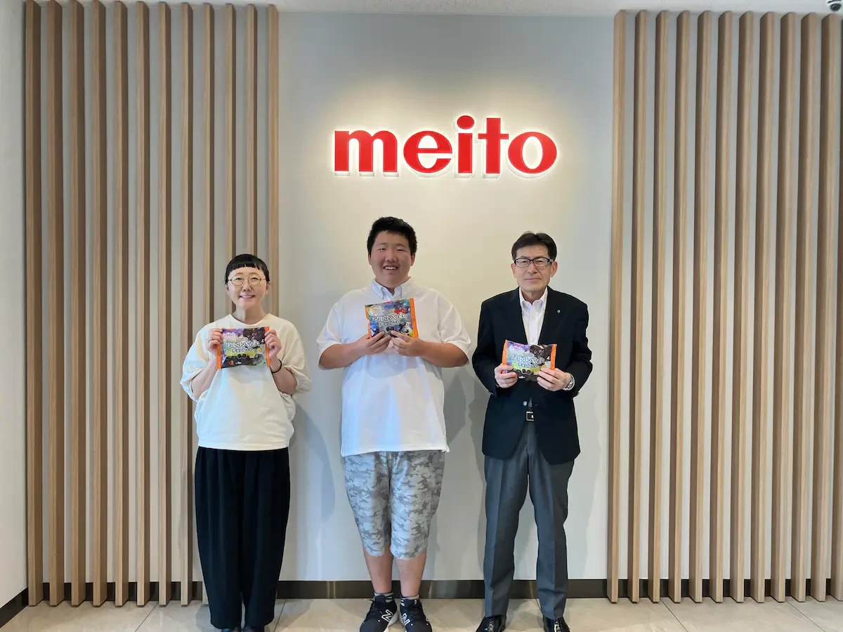 アルファベットチョコレートの商品を手に持ちながら三矢社長、伊山英吾さん、伊山さんのお母さまの3名が映った集合写真