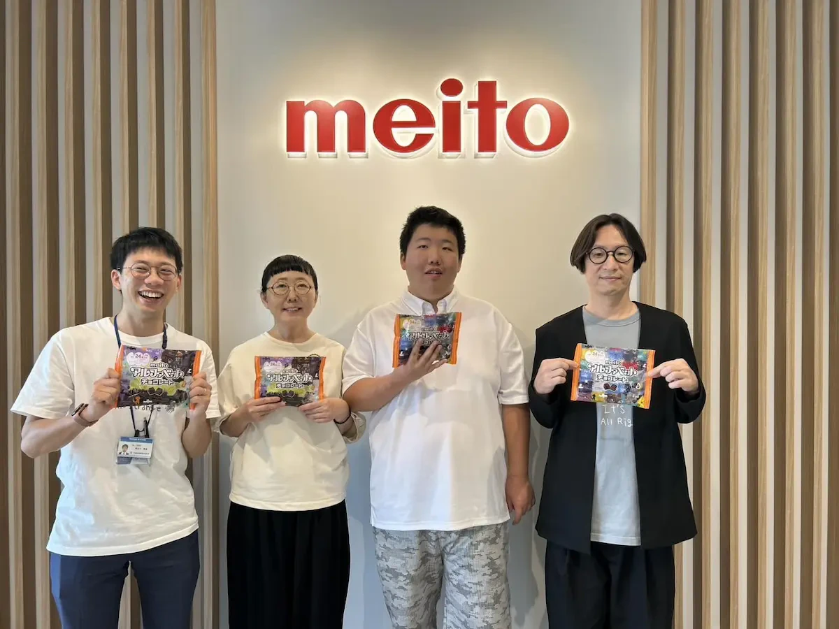 名糖産業株式会社様の企業ロゴマーク看板の前で、伊山英吾さん、伊山さんのお母さまと当社男性社員2名が映った集合写真