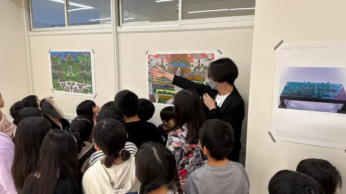 展示されているアール・ブリュット作品について、当社男性社員が学生たちに囲まれながら説明している様子の写真