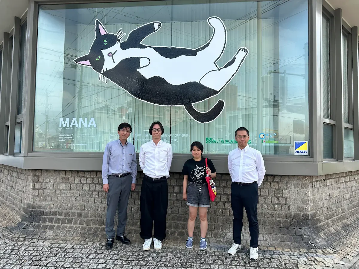 ウインドウラッピングデザインされた作品の前で荒木麻奈さんをはじめ総勢4名が映った集合写真