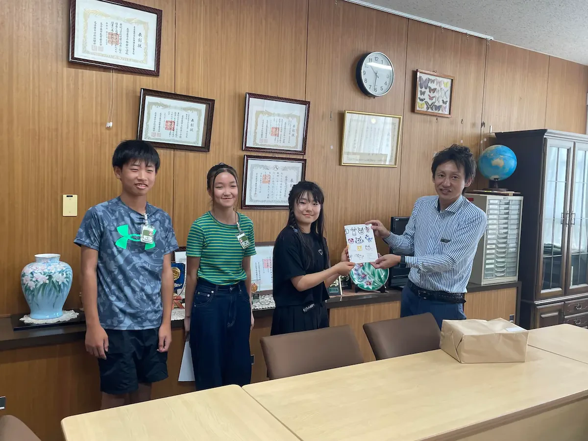 白金小学校にて、生徒たちに「残紙ノート」を渡している様子の写真