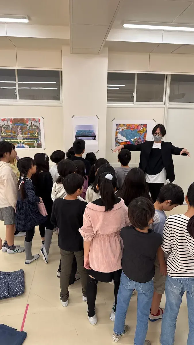 展示されている作品の前で学生たちと対話をしながら作品を紹介している様子の写真